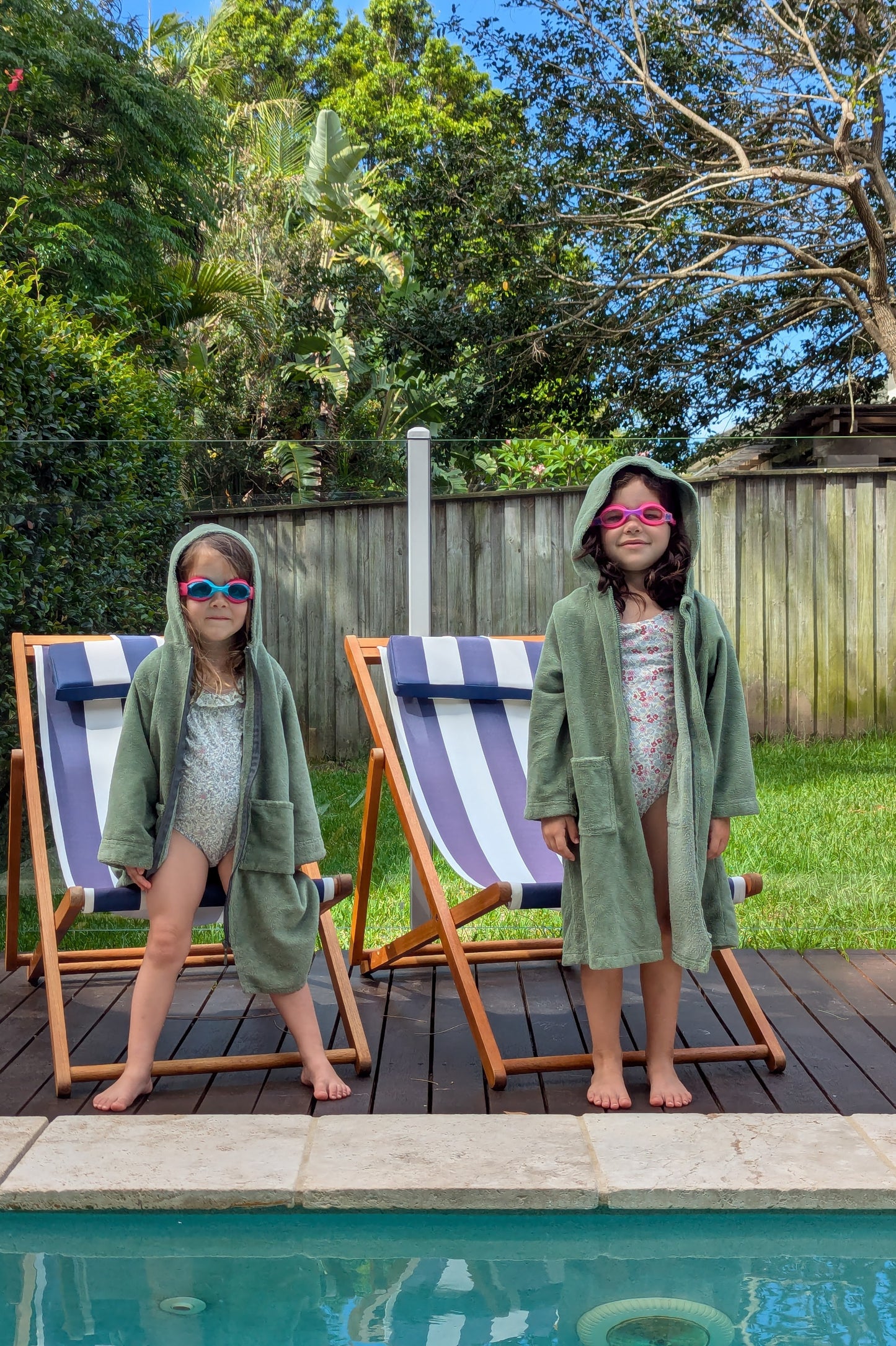 Toddlers wearing cactus hooded towels by the swimming pool.