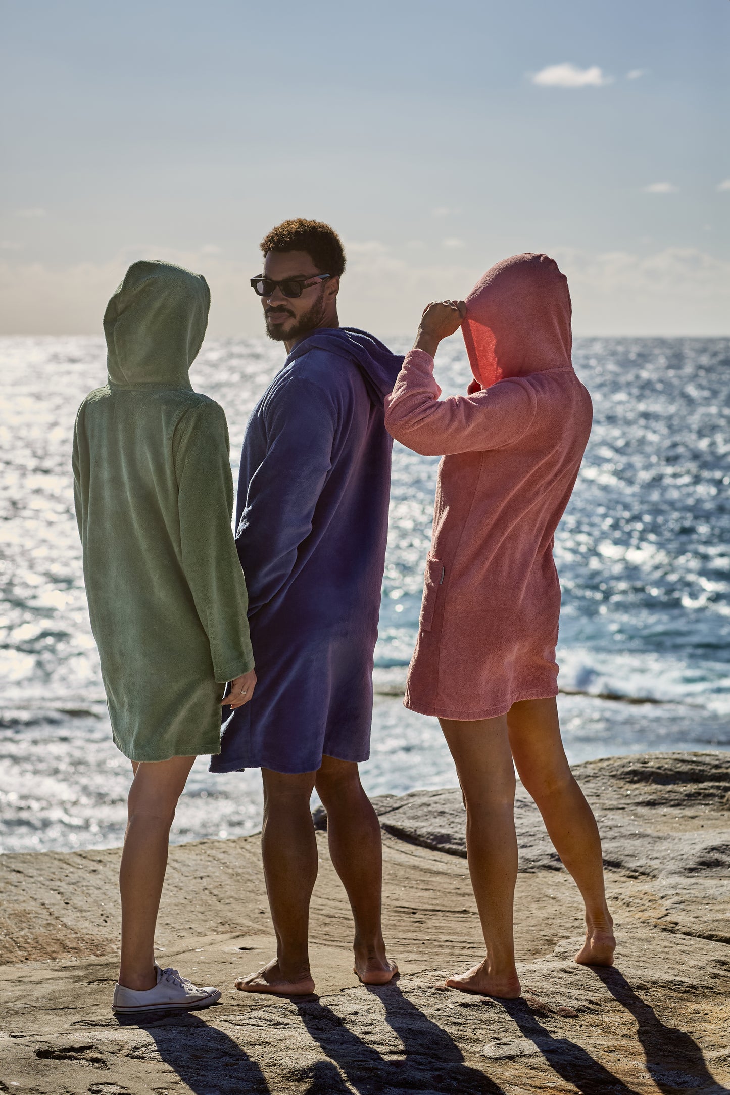 A man and two women chilling by the ocean, with their CAPIMIRI garment on.