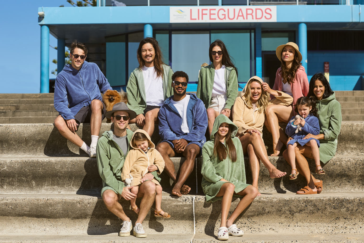 Group of people wearing CAPIMIRI hooded towels, from babies to seniors.