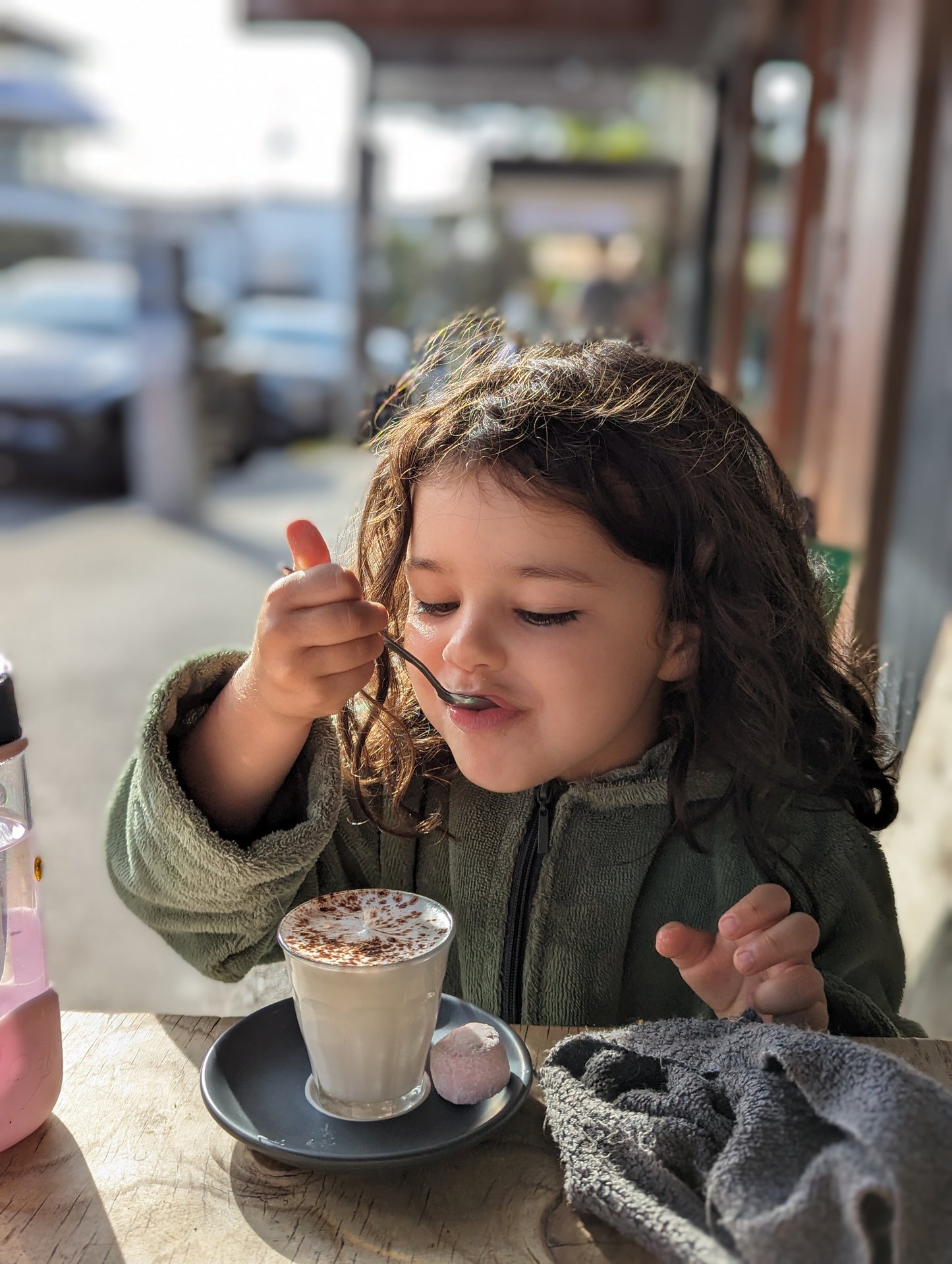 Toddler wearing cactus hooded towels while having a hot chocolate at a coffee in Bondi Beach.