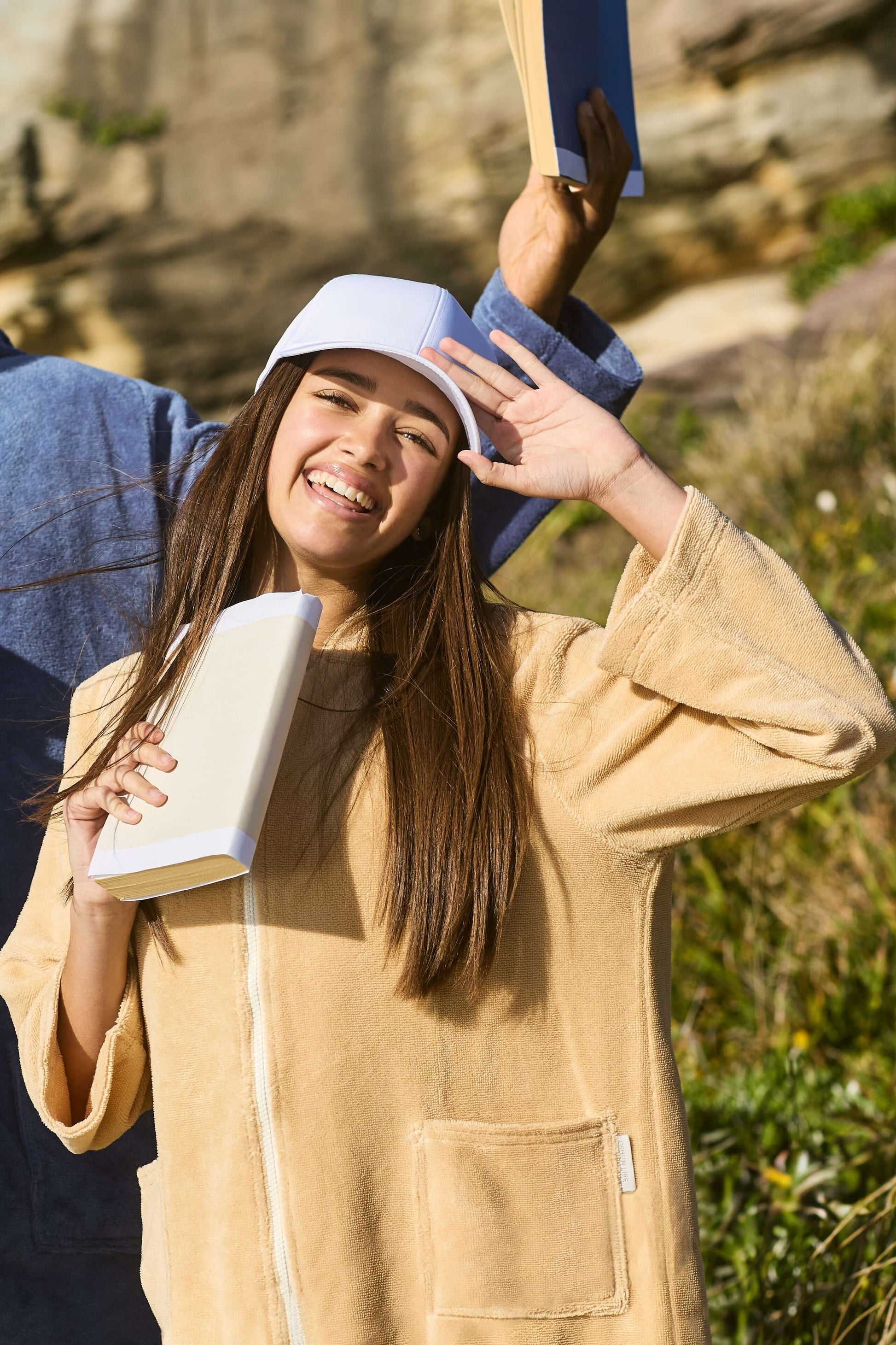 Young lady holding a book in her beige poncho. Sandcastle Pre Teens & Teens