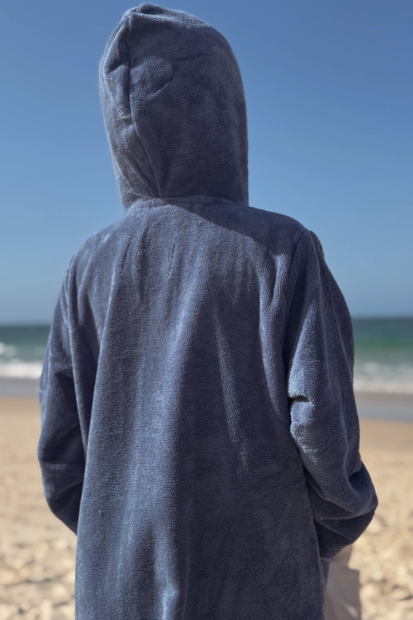 Kid wearing a blue hooded towel on a beach
