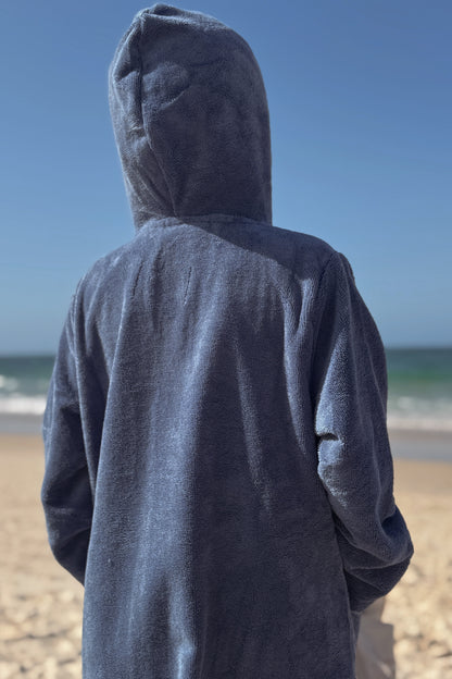 Kid wearing a blue hooded towel on a beach