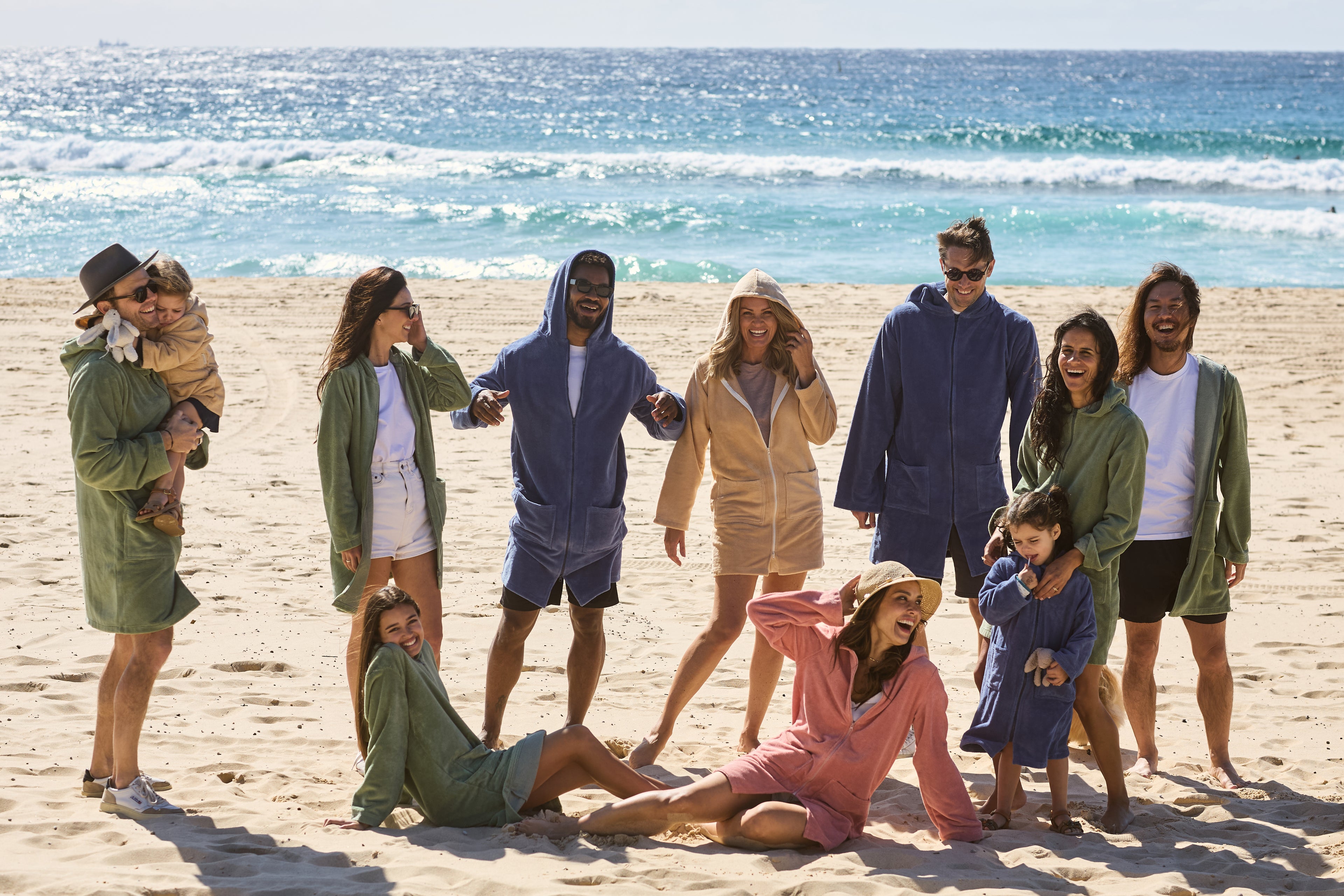Group of people wearing Capimiri hooded towel robes enjoying a sunny beach day
