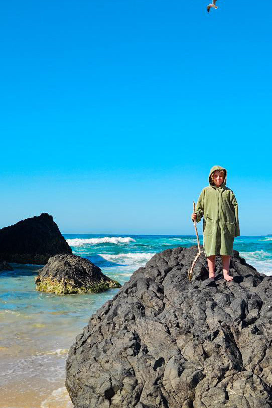 Child wearing Capimiri green hooded towel robe at the beach